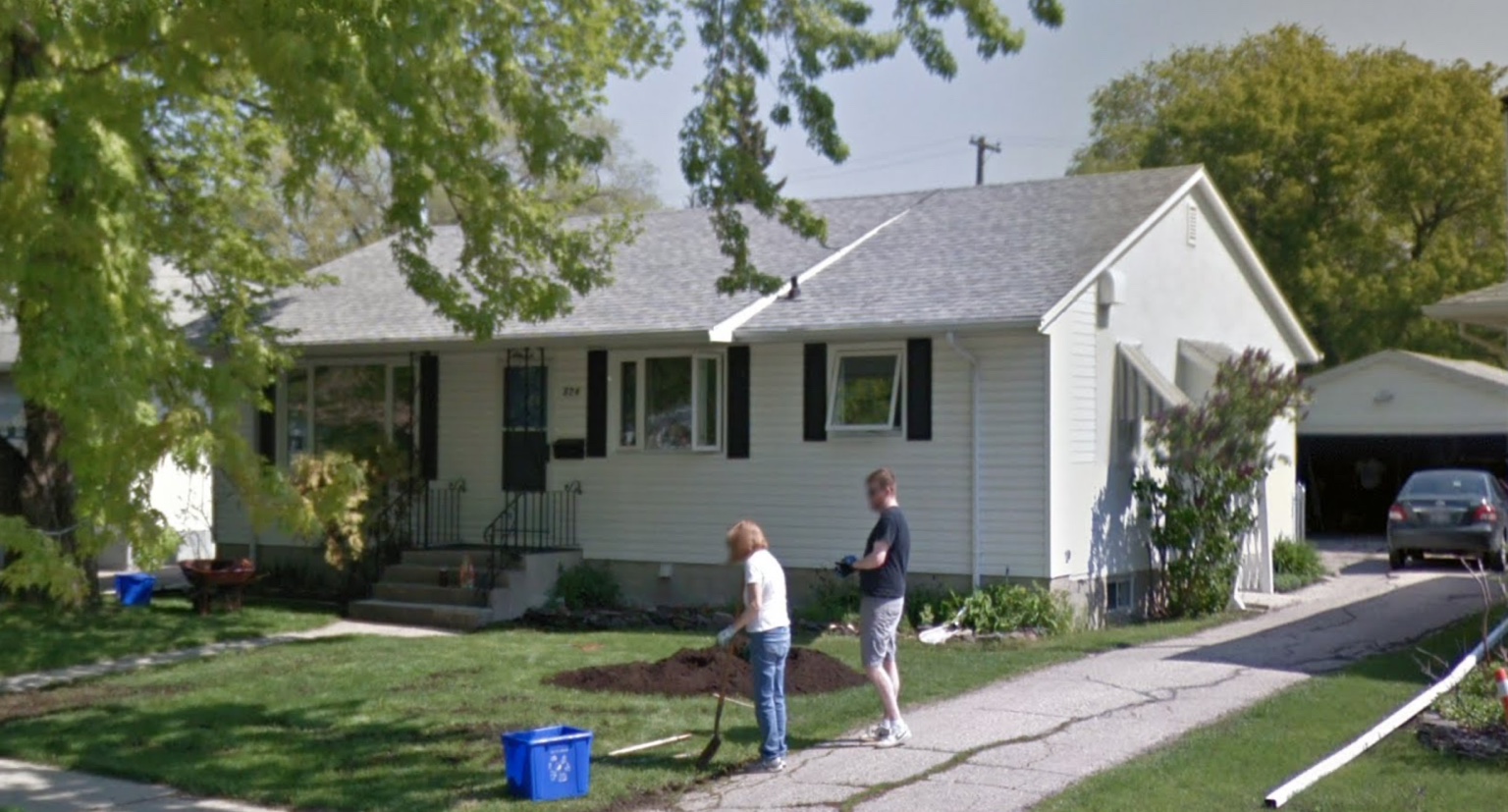 Christine's grandparents' white bungalow with family working in the front yard